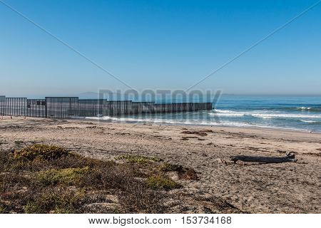 Border Field State Park beach with the international border wall separating San Diego, California and Tijuana, Mexico in the distance.