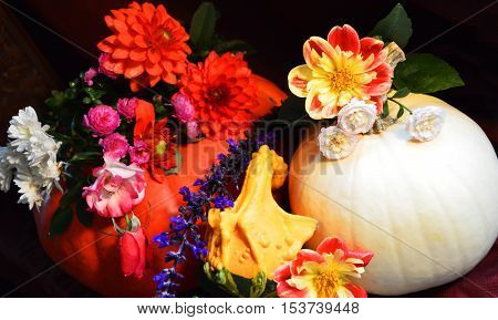 Beautiful Floral Pumpkin Centerpiece with autumn harvest colorful red and white pumpkins, gourds and autumn flower bouquet including roses and chrysanthemums in an abundance of color celebrating the fall season