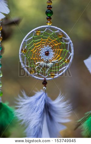 photo of a dreamcatcher made by hand with using threads beads and feathers rooster