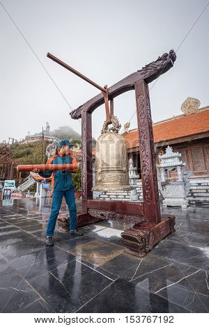 Sa Pa Vietnam - September 18 2016: Staff man ring a big golden bell in front of temple of Fansipan legend of Sa Pa Vietnam before sunset.