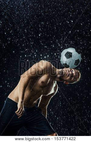 Water drops around football player on black background