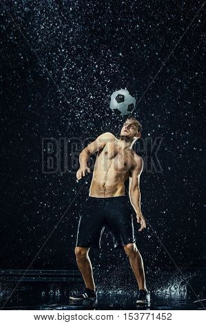 Water drops around football player on black background