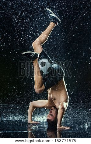 Water drops around football player on black background