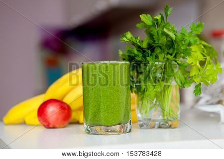 green smoothie with fruits and vegetables on the kitchen table