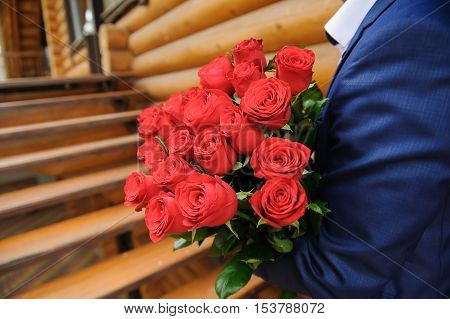 Man with a large bouquet of roses. Groom holding a bouquet of red roses.