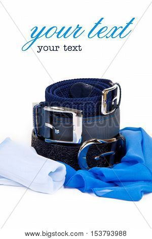 Three leather belt in a row on top of each other on a white background with a metallic blue silk scarf female buckles. Clothing accessories