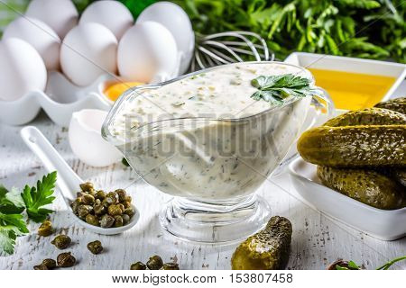 Homemade sauce tartar tartara with ingredients eggs olive oil lemon, capers, parsley, pickles on white background