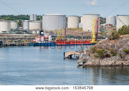 Tanker unloading with oil storage tanks in the background
