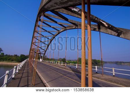 Road and a small suspension bridge in countryside of Thailand.
