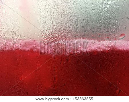 Close up of Red Water pouring and splashing with Bubble and Dew Point on glass