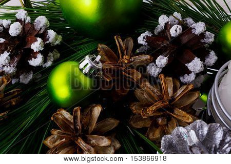 Christmas background with snowy pinecone and green ornaments. Christmas party decoration with shiny balls.