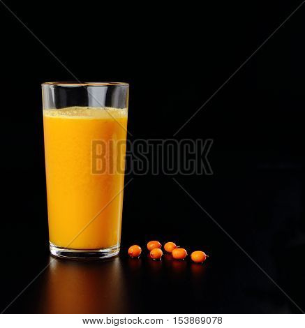 juice from a sea- buckthorn with berries on a black background