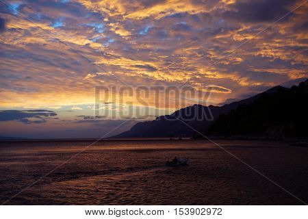 Spectacular dramatic dark sky with clouds over grey sea horizon on evening seascape on natural background with boat
