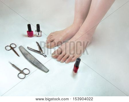 Feet need a pedicure. Legs with long nails and Tools for manicure(pedicure) on white background