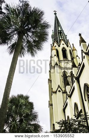 Vertical view of a historical Spanish style church tower with palm tree Savannah USA
