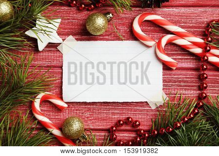 Christmax Tree Branch With Baubles, Candies On Red Wooden Table