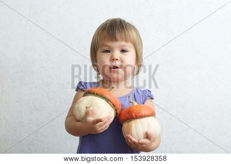 Little Child Girl Holding Two Decorative Pumpkins