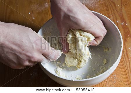 The man preparing the dough in the kitchen. Kneading the dough for pastry cakes pizza and ravioli. Hands close-up. wooden background. Craftsmanship. Restaurant and homemade tasty food.