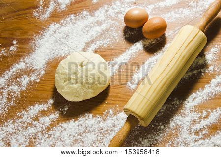 Eggs rolling pin and dough on the wooden table in the kitchen. Ingredients for baking dough. Still life in a rustic style.