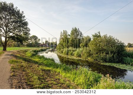 Rural Landscape With A Small Reflecting Stream In The Low Sunlight Of A Summer Evening. The Photo Wa