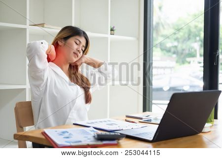 Asian Businesswoman Touching Massaging Stiff Neck To Relieve Pain In Muscles Working In Incorrect Po