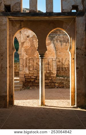 View From Inside Of The Ruins Of A Building. Double Gate With Archs. Windows Above. Sunlight On The 