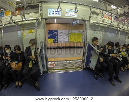Tokyo, Japan - April 27, 2016: Japanese Salary Man Sleeping Or Using Their Phone In Subway While Doo