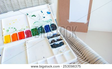 Watercolor Painting Tray On The Chair In Front Of Drawing Board On The Wall
