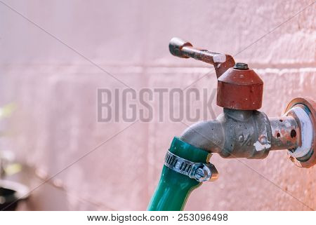 Closeup Water Tap On The Wall Connected With Green Rubber Tube