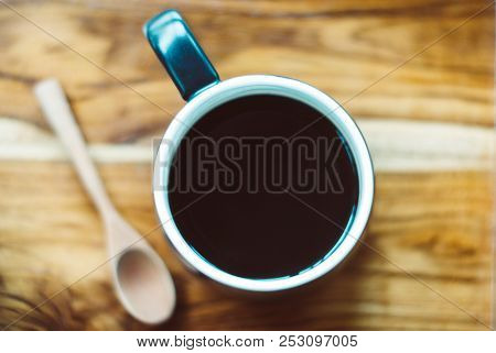 Top View Photo Of Black Mug, White Inside Full Of Hot Espresso Coffee, Beside Of It Is Wooden Spoon 