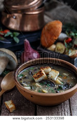 Mushroom Soup In Ceramic Bowl With A Copper Pan And Mushroom In Background, Dark Photo.
