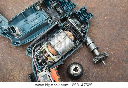 Parts Of Disassembled Electric Drill On Rusted Background.