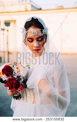 Beautiful Eastern Style Bride With White Veil And Hairpiece Holding Bridal Bouquet Posing Outdoors A