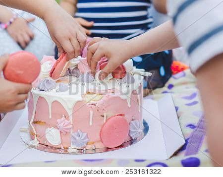 Group Of Children Eating Cake Outdoors By Fingers. Close-up.