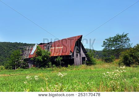 Arkansas Barn, In The Ozark Mountains, Is Broken And Dilapidated.  Tin Is Torn Away From Roof By Win