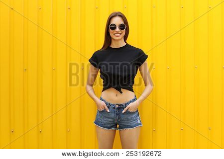 Young Woman Wearing Black T-shirt Near Color Wall On Street