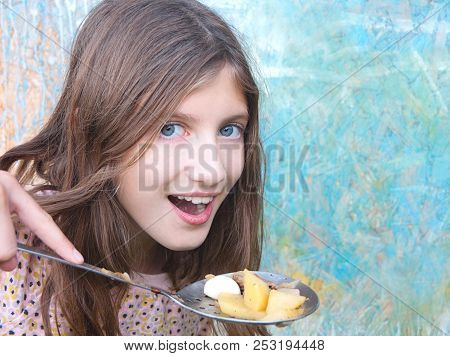 Teenage Girl With Long Hair Holding A Laddle With Just Cooked Potato, Meat And Garlic