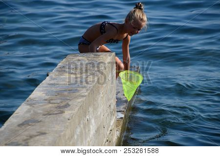 Novorossiysk, Russia - August 06, 2018: Children Catch A Net Of Small Fishes In Sea Water.