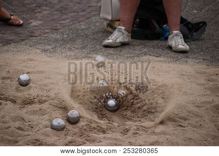 Sand Is Flying Away When Ball Is Landing On The Ground During Boules Game.