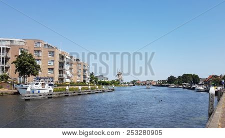 River Vliet In Leidschendam With Blue Sky And Windmill Salamander On The Background In The Netherlan