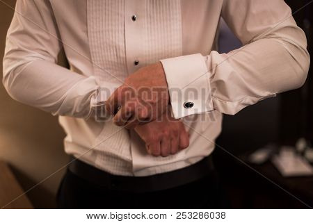 Man In Dress Shirt Doing Up Cufflinks.