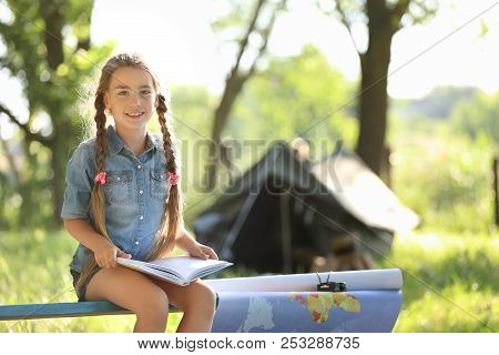 Little Girl With Map And Book Near Tent Outdoors. Summer Camp