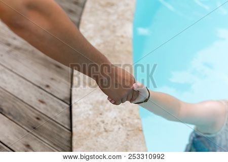 Man Hand Reach Helpnig Achild In A Local Pool On Vacation.