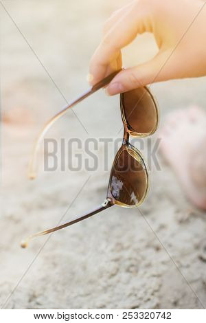 Photo Of Woman's Hand Holding Sunglasses Against Sand