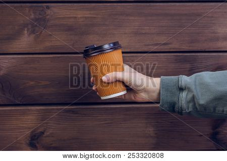 It's Coffee Time! Woman's Hand Holding Paper Cup Of Fresh Coffee Against Dark Wooden Background