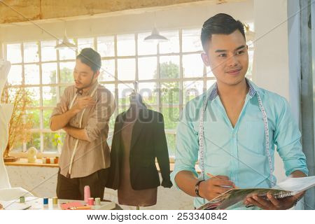 Young Asian Male Desiner Standing With Desiner Team Working In The Studio.