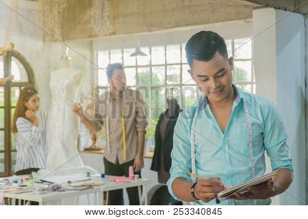 Young Asian Male Desiner Standing With Desiner Team Working In The Studio.