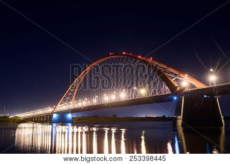 Bridge over the river Ob night. The lights of the bridge glow in the night sky.