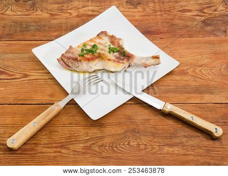 Grilled Pork Loin Chop With Partly Frenched Rib And Sprinkled With Chopped Dill On White Square Dish