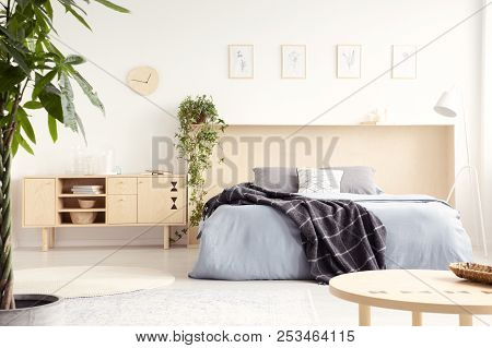Real Photo Of Bright Bedroom Interior With Wooden Cupboard With Books And Decor, Simple Posters And 